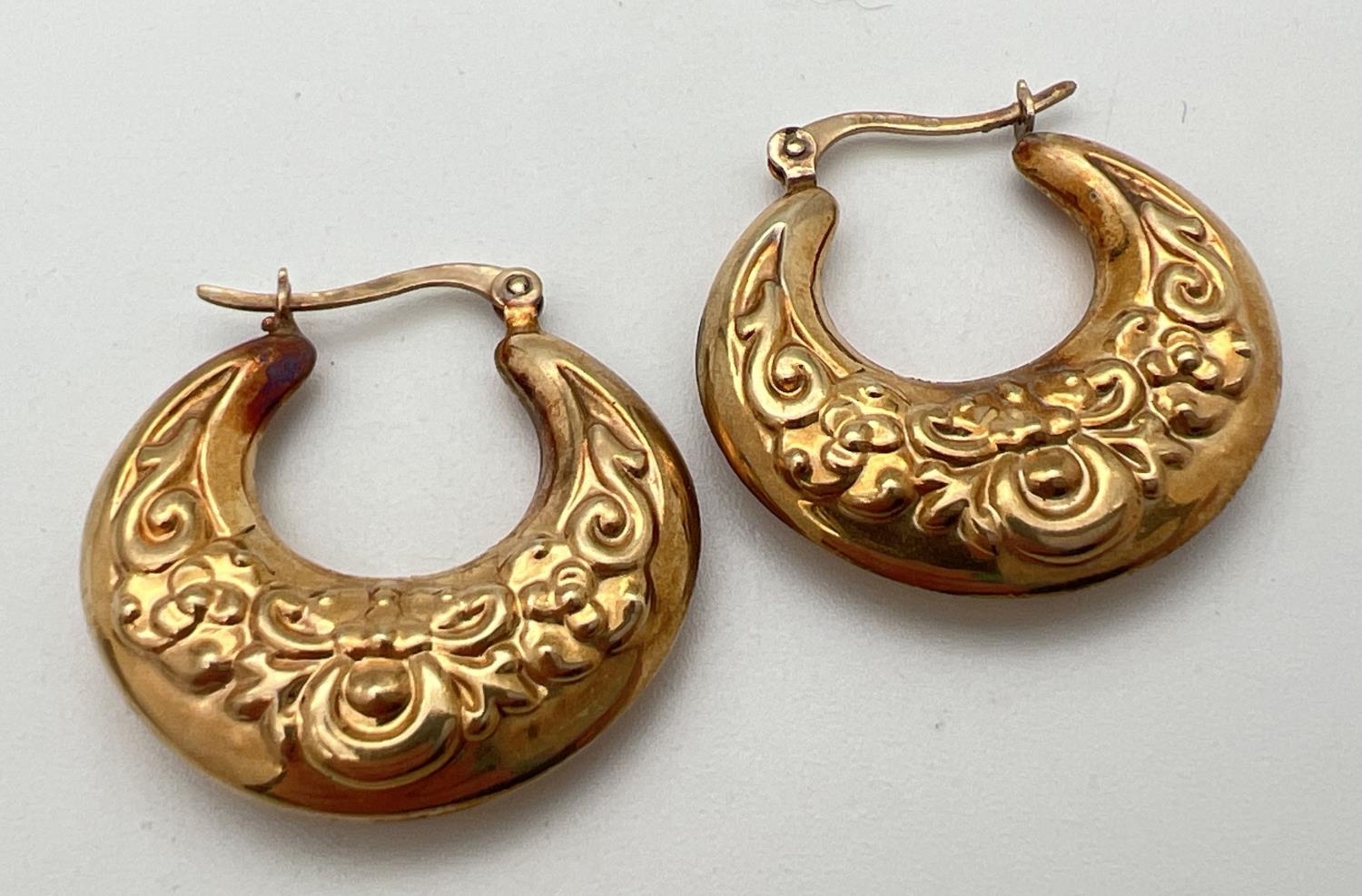 A pair of 9ct gold creole style earrings with floral pattern and hinged posts. Approx. 2.75cm - Image 2 of 3
