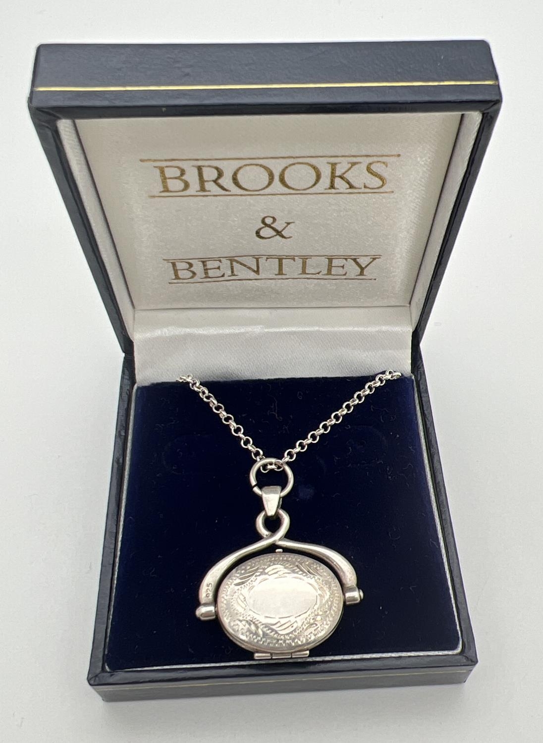 A boxed silver oval shaped spinning locket on an 18" belcher chain with spring ring clasp. Pendant