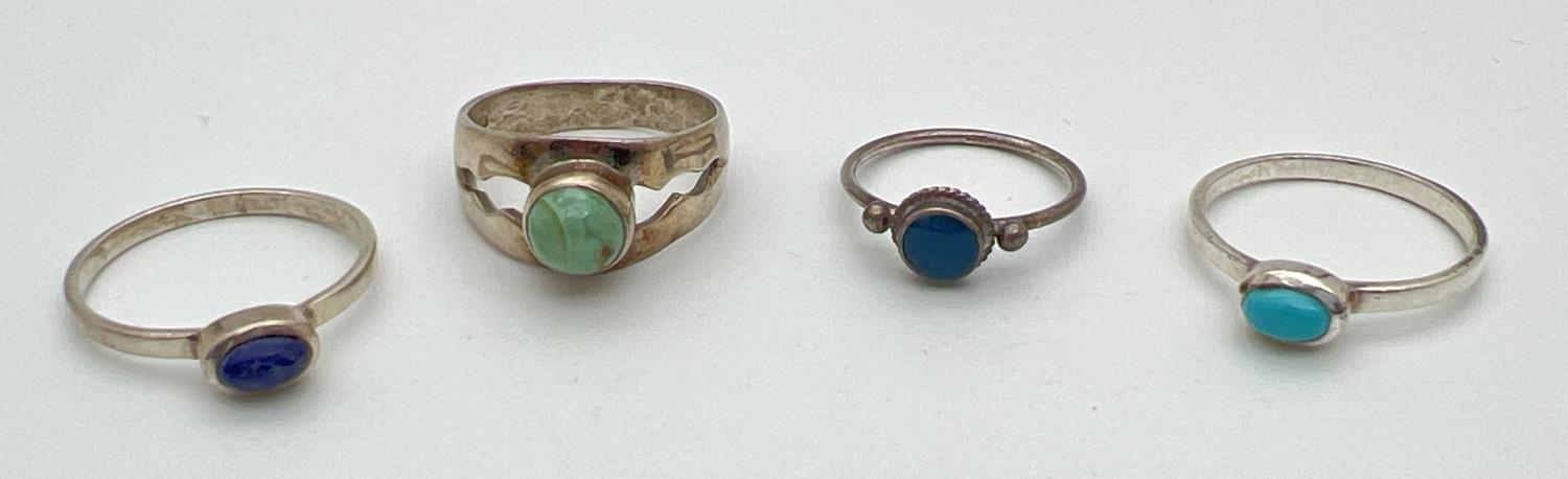 4 silver dress rings each set with a single cabochon stone. To include Turquoise and Lapis Lazuli.