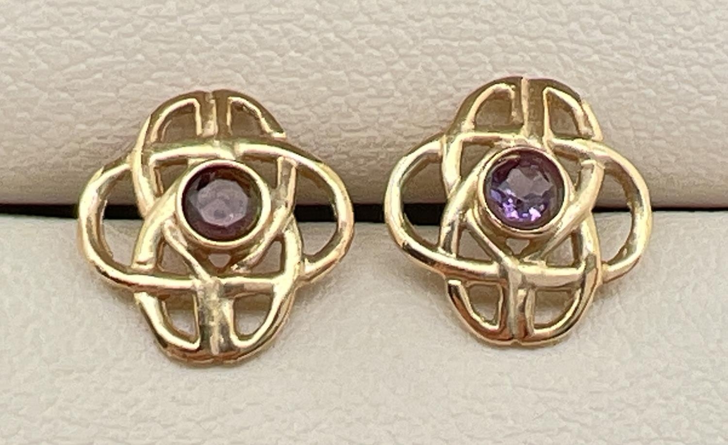 A pair of gold pierced work Celtic design stud earrings set with a small round cut amethysts. Gold