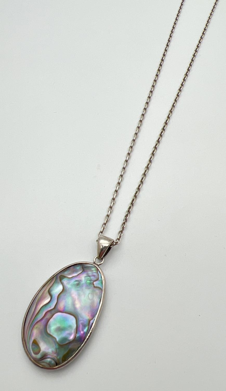 An oval shaped Abalone shell pendant set in silver, on a 20" belcher chain with spring ring clasp.
