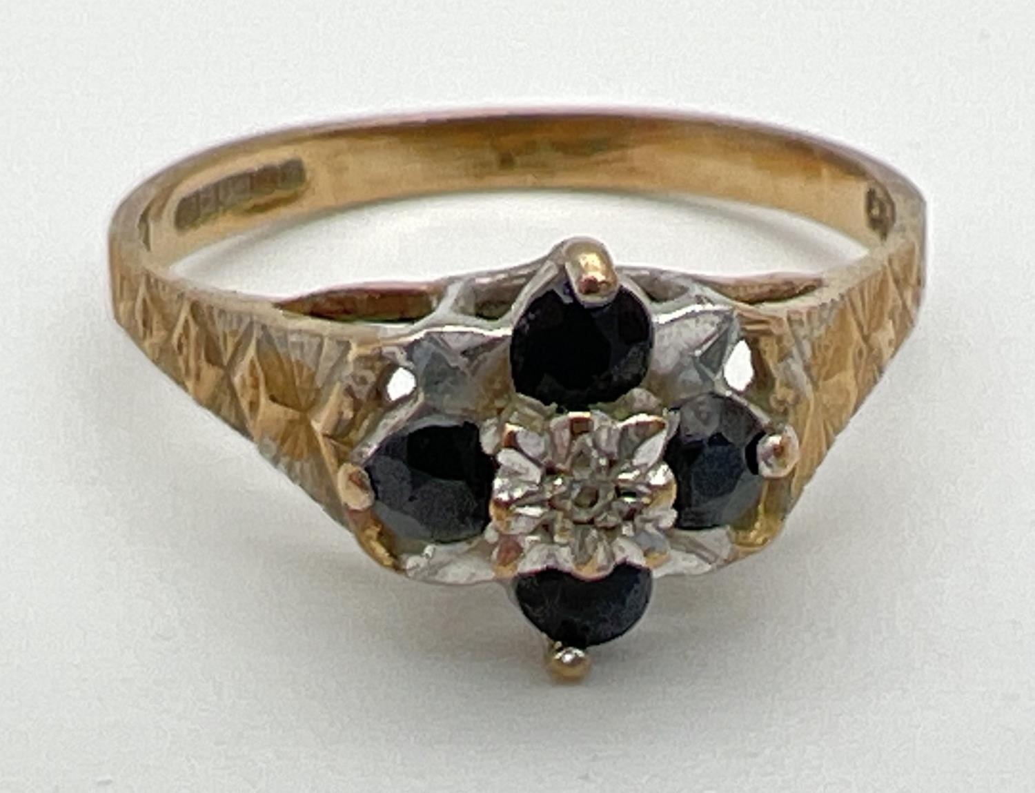 A vintage 9ct gold sapphire and diamond dress ring. A small central round cut diamond surrounded