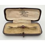 An antique 9ct gold bar brooch set with a central round cut garnet and 2 small seed pearls to both