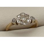 An Art Deco 18ct gold and platinum diamond set ring. Floral style mount set with 7 small round cut