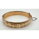 A vintage 9ct rolled gold bangle with half floral engraved pattern, push clasp and safety chain.