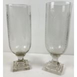 A pair of cut glass vases raised on pedestal stems with foliate design. Approx. 34cm tall.