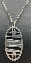 A Scottish silver contemporary oval pendant with pierced work design, on a 24" belcher chain with