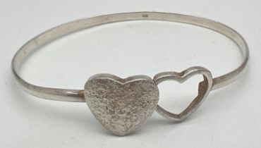 A modern design double heart silver bangle with hook clasp. Central brushed silver and open work