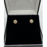 A pair of 18 ct gold circular studs each set with a single round cut white sapphire. Gold marks to