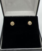 A pair of 18 ct gold circular studs each set with a single round cut white sapphire. Gold marks to