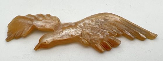 An Art Nouveau carved horn brooch modelled as a bird in flight, with pearlised finish. Approx. 9.5cm