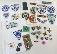 A collection of Emergency services and health care service cloth badges, cap badges pin badges and