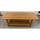 A modern Ercol light wood coffee table with rounded edges, undershelf and cylindrical legs.