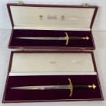 2 boxed Wilkinson Sword presentation Daggers, with wood effect handles and brass fixings.