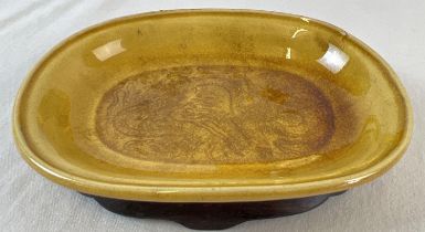 A small Chinese ceramic shallow bowl with amber coloured, on a shaped wooden stand. Chinese dragon