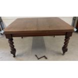 An antique dark oak wind out, extending dining table with barley twist legs raised on square