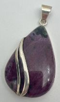 A silver teardrop shaped pendant set with ruby Zoisite with simple twist design overlay. Silver mark