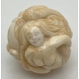 A carved bone netsuke of spherical form, carved as mermaids. Small signature mark to underside.