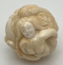 A carved bone netsuke of spherical form, carved as mermaids. Small signature mark to underside.