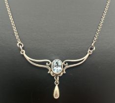 An Art Nouveau design silver fixed pendant necklace set with an oval cut blue topaz and a small