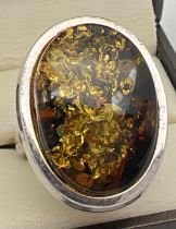 A large modern design silver dress ring set with an oval amber cabochon. Silver mark to outside of