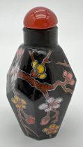 A small black ceramic hexagonal shaped snuff bottle with hand painted floral decoration. Approx. 6.