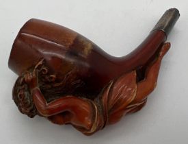 An antique Meerscham style pipe with carved figurehead of a woman holding a cornucopia of flowers.