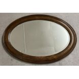 A vintage dark oak framed oval shaped hall mirror with bevel edged glass. Approx. 86.5cm x 62cm.