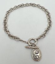 A silver belcher style chain bracelet with T bar clasp and oval charm decorated with star & swirl