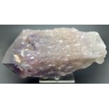 A large Brazilian raw amethyst point with stand. Small natural orange/brown inclusions throughout.