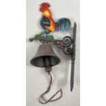 A wall mountable cast iron garden bell with painted cockerel detail and leather strap bell pull.