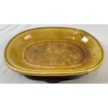 A small Chinese ceramic shallow bowl with amber coloured glaze, on a shaped wooden stand. Chinese