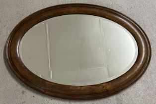 A vintage dark oak framed oval shaped hall mirror with bevel edged glass. Approx. 86.5cm x 62cm.