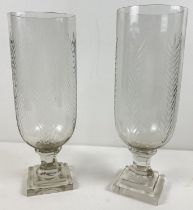 A pair of cut glass vases raised on pedestal stems with foliate design. Approx. 34cm tall.