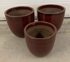 3 modern dark red glazed garden pots. A pair of large pots together with a smaller pot. Largest