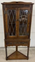 A vintage dark oak Old Charm corner unit with leaded glass doors and turned front legs. Carved
