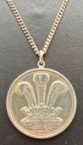 A vintage silver circular pendant with Welsh Dragon to one side and Prince Of Wales feathers to