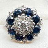 A vintage white gold diamond and sapphire cluster ring. Set with 17 round cut diamonds in varying
