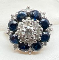 A vintage white gold diamond and sapphire cluster ring. Set with 17 round cut diamonds in varying