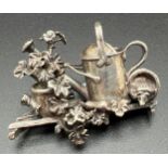 A boxed silver brooch in the shape of a watering can with geraniums, flowers pots and a hedgehog, by