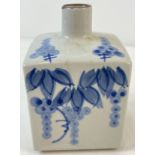 A square shaped blue and white oriental ceramic vase with floral design to top and 3 sides.