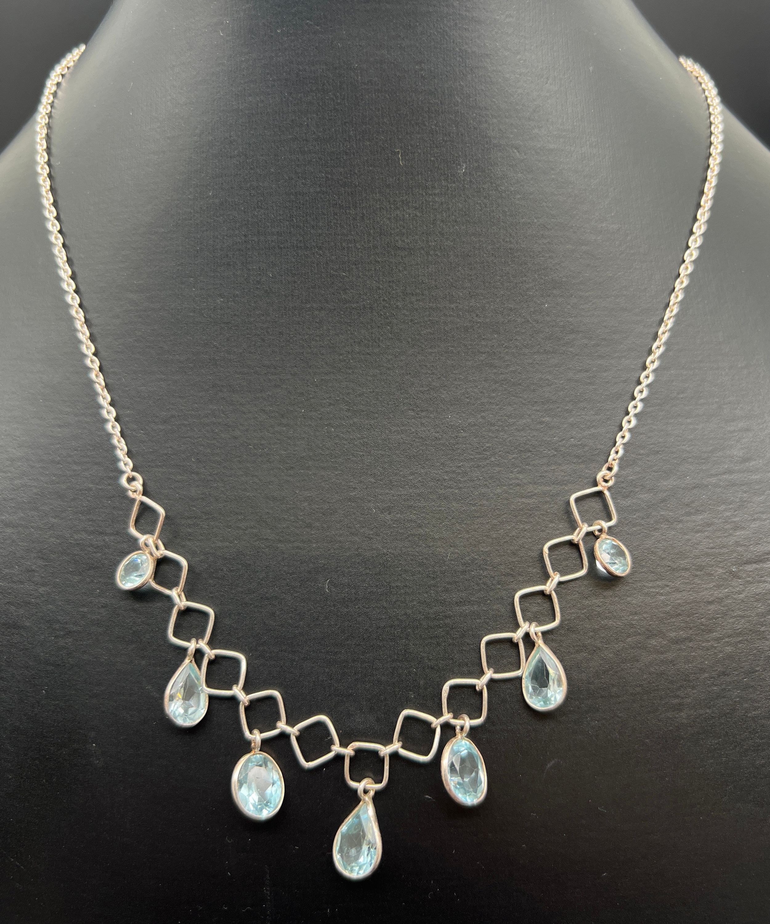 A modern design 18 inch fixed pendant silver necklace with round, oval and teardrop cut blue topaz