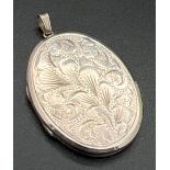 A large vintage silver oval shaped locket with floral engraving to front and engine turned