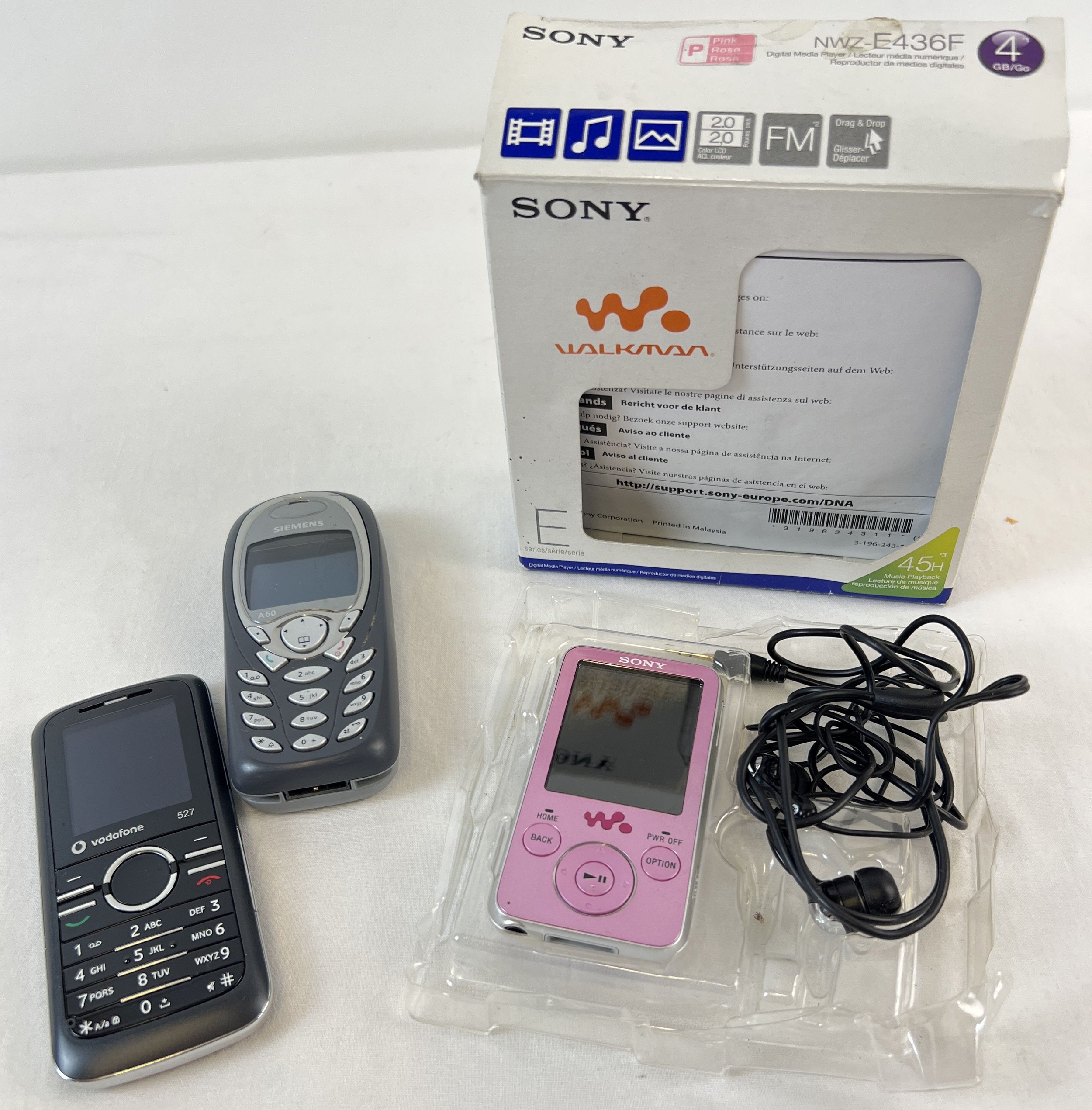 A boxed Sony Walkman with headphones, in pink (NWZ-E436F). Together with a Vodafone 527 mobile phone