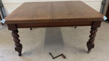 An antique dark oak wind out, extending dining table with barley twist legs raised on square
