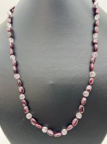 A 20 inch garnet and clear bead necklace with white metal push clasp.
