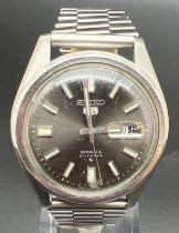 A vintage Seiko 5 automatic wristwatch with stainless steel strap and case. Black face with luminous