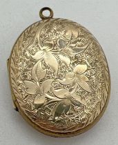 A yellow metal (front and back) oval locket with floral decoration to front and foliate & scroll