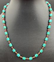 An 18" Chinese turquoise and garnet beaded necklace with gold tone T bar clasp with floral detail.