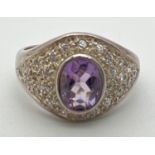 A silver, amethyst and cubic zirconia dress ring with central bezel set oval cut amethyst. Set